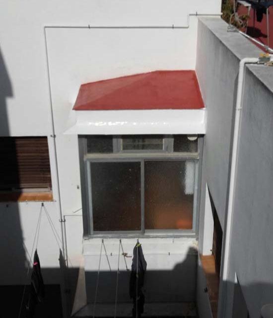 Un edificio blanco con un techo rojo y una ventana.