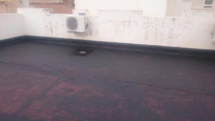 Una azotea con un techo negro y una pared blanca con grafitis.