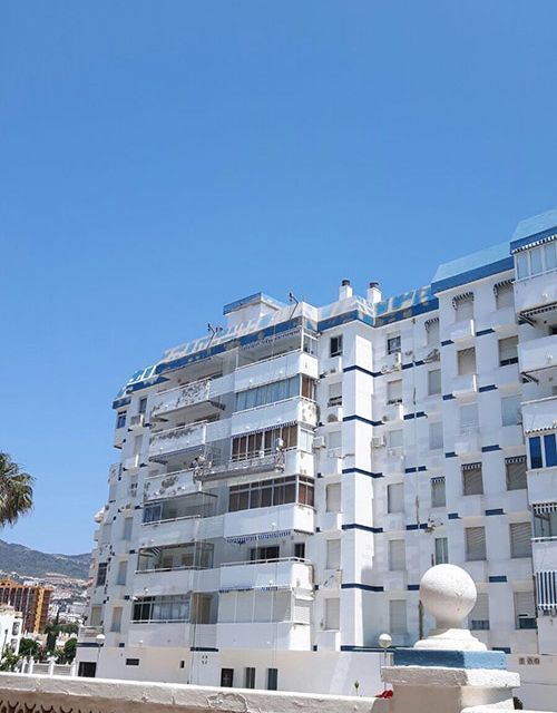 Un gran edificio blanco con balcones y un cielo azul al fondo.