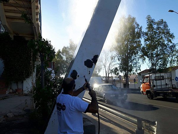 Un hombre está rociando pintura sobre un poste blanco.