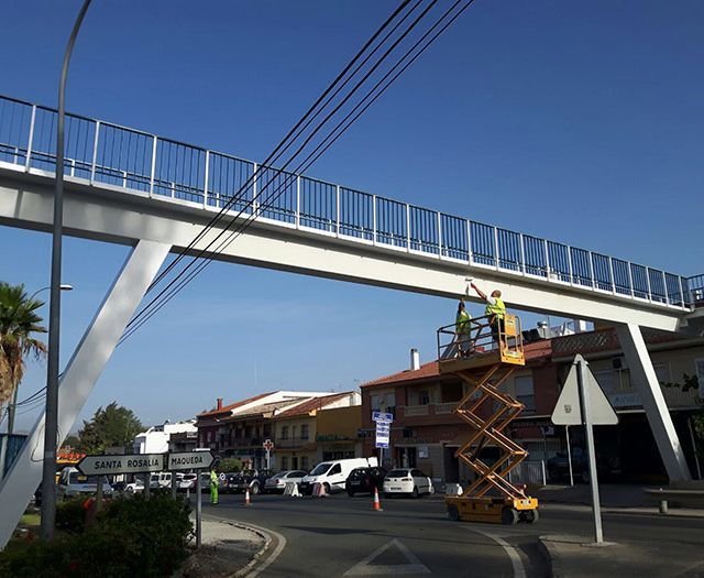 Un hombre en un ascensor está trabajando en un puente sobre una calle.