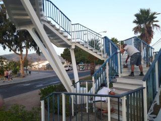 Un hombre está pintando la barandilla de un puente.