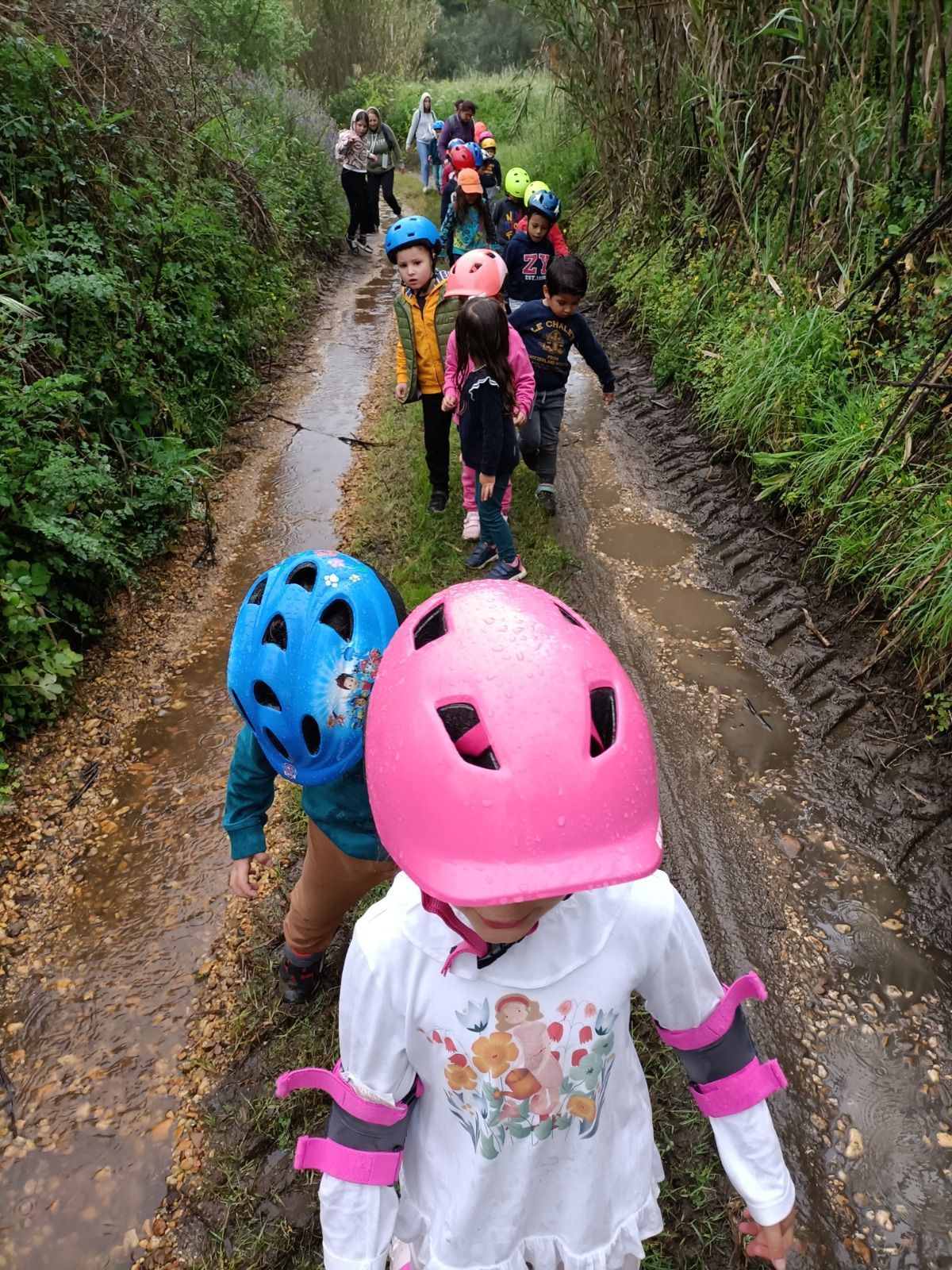 Um grupo de crianças está caminhando por um caminho lamacento.