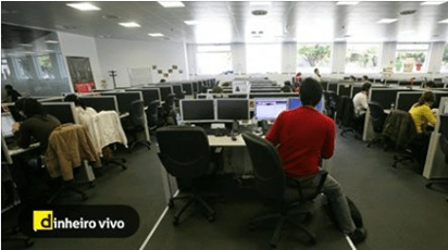 Um homem sentado a uma mesa num escritório com uma placa que diz dinheiro vivo