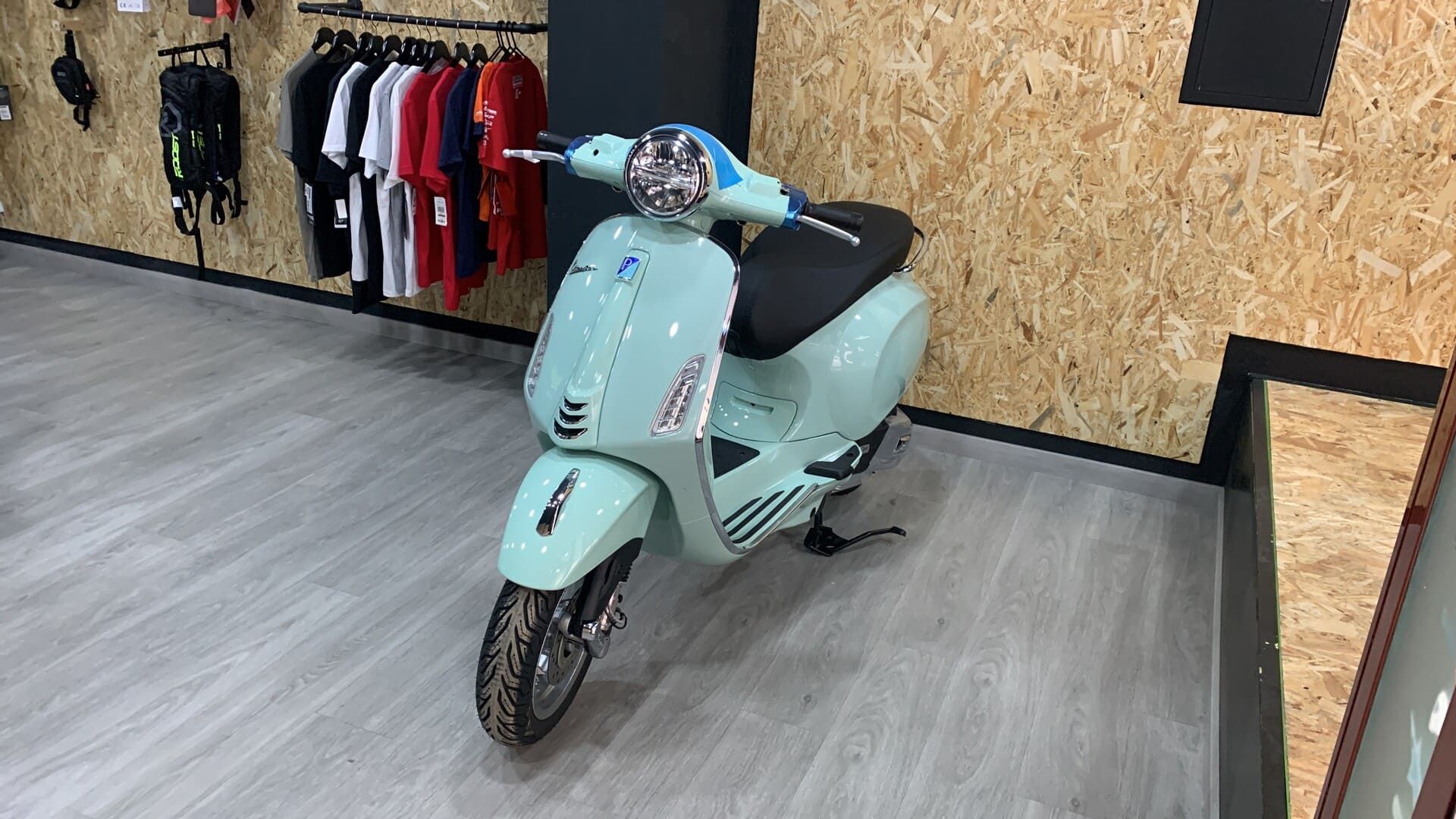 Un scooter está estacionado en una habitación con ropa colgada en la pared.