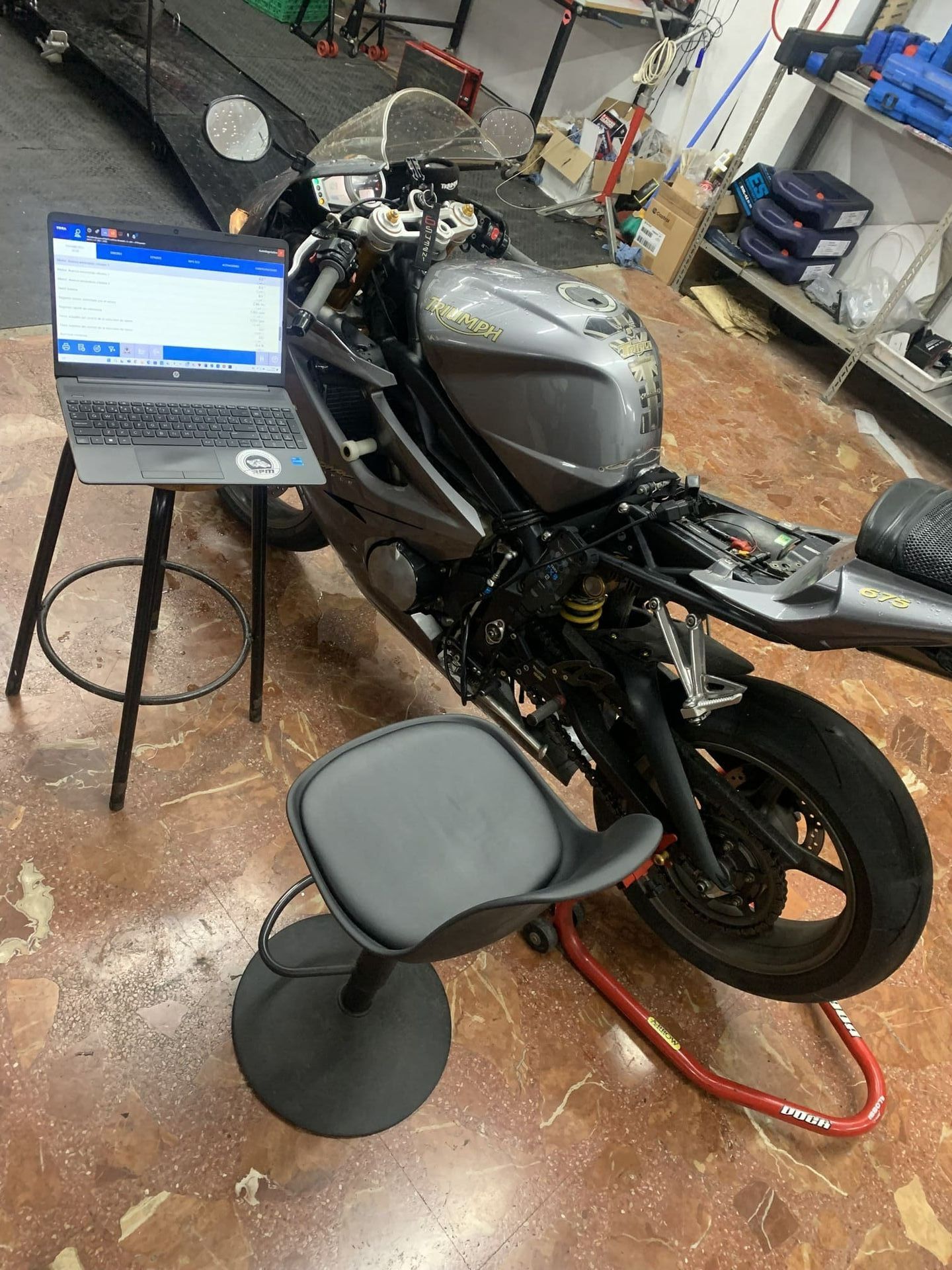 Una motocicleta está sentada en un soporte al lado de una computadora portátil sobre una mesa.