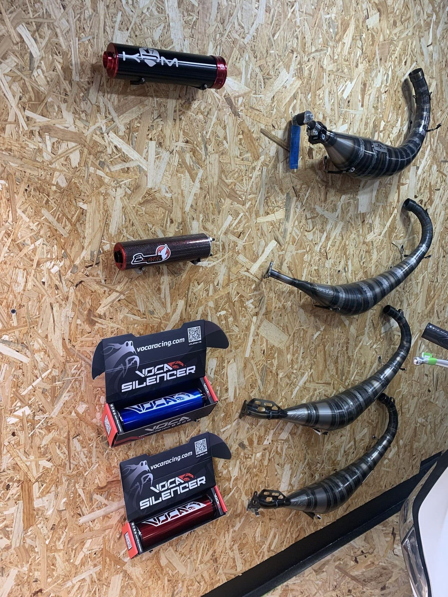 Un montón de tubos de escape están colgados en una pared de madera.