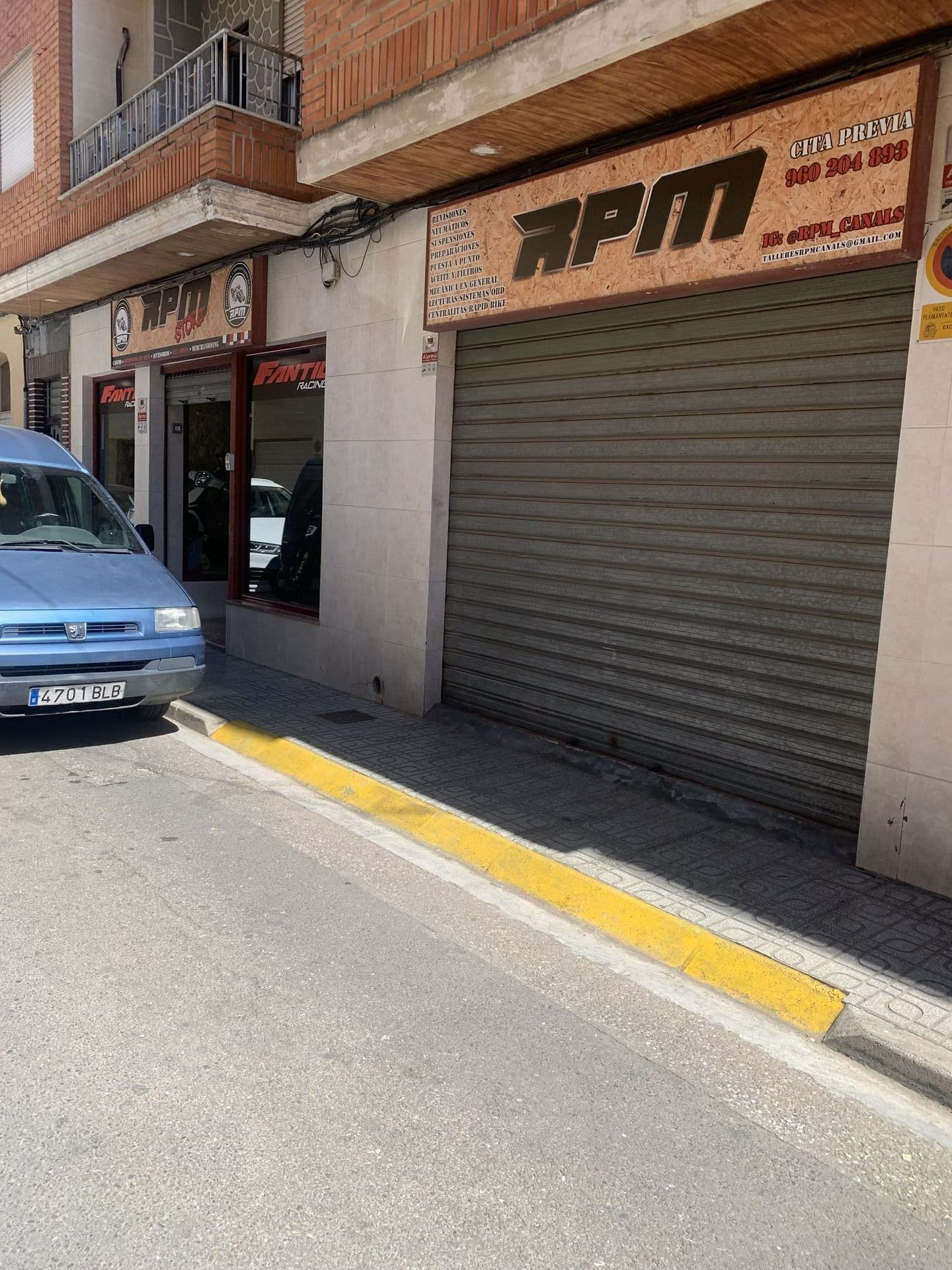Una camioneta azul está estacionada frente a una tienda APM.