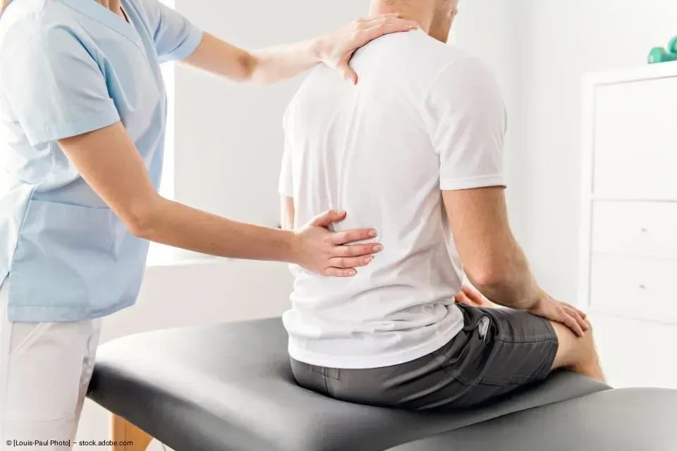 Eine medizinische Fachkraft untersucht den Rücken eines Patienten in einer Klinik.