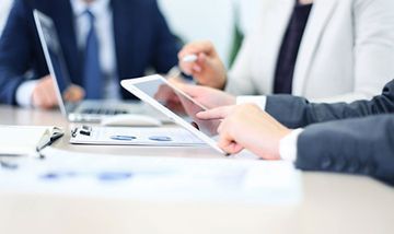 Un grupo de gente de negocios está sentado en una mesa mirando una tableta.