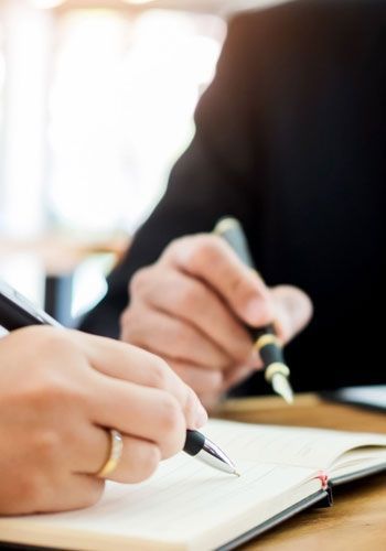 Una persona está escribiendo en un cuaderno con un bolígrafo.