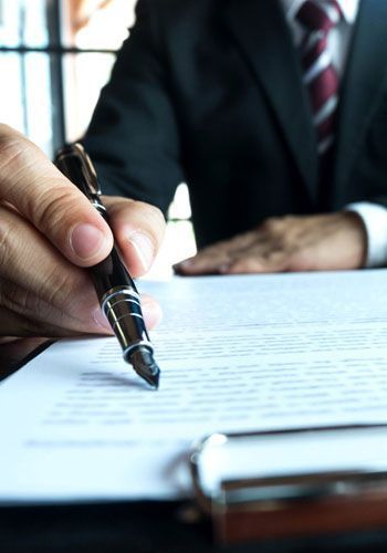 Un hombre con traje y corbata está firmando un documento con un bolígrafo.