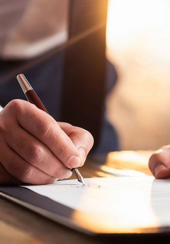 Una persona está escribiendo en un trozo de papel con un bolígrafo.