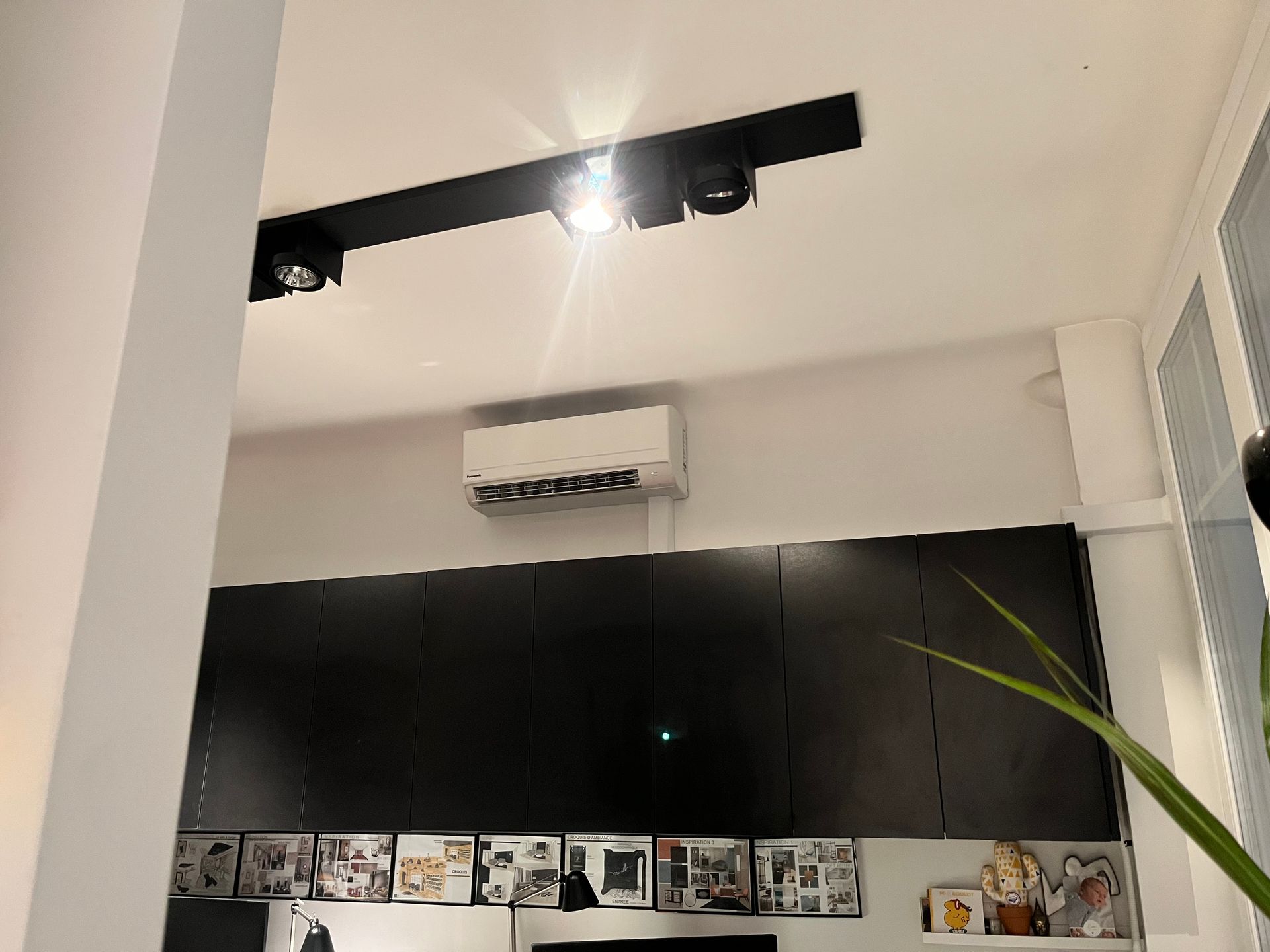 Climatiseur accroché en haut d'un mur, près du plafond et au-dessus de placards noirs