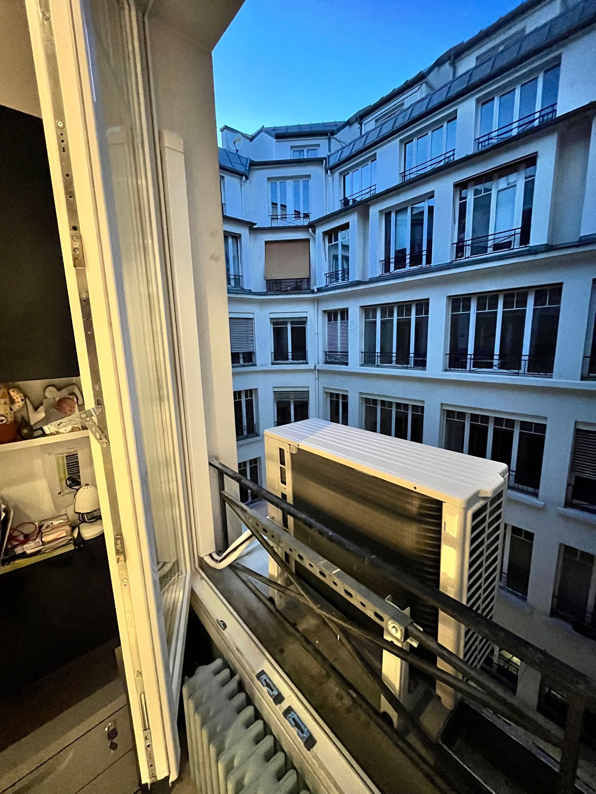 Pompe à chaleur accrochée au garde-corps d'une fenêtre