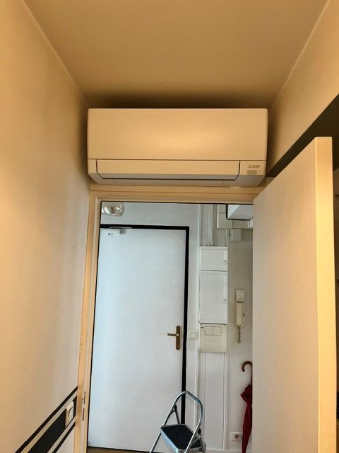 Climatisation murale placée au dessus d'une porte blanche