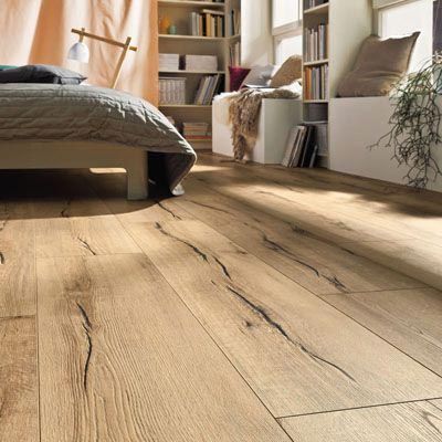 Intérieur de chambre avec parquet clair, lit et bibliothèque.
