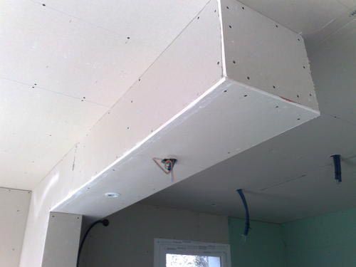 Boîtier en plaques de plâtre fixé au plafond, entourant les spots encastrés et le câblage. Construction blanche, non finie.