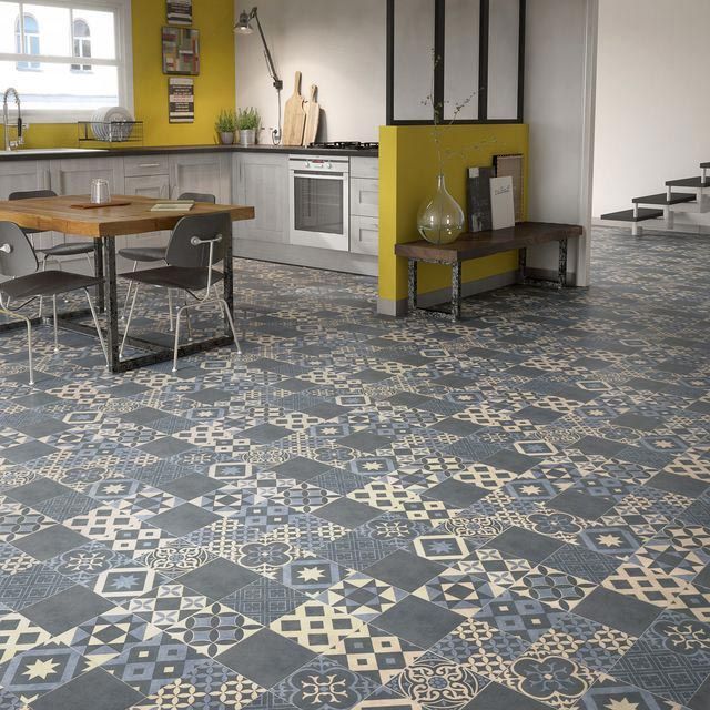 Cuisine avec sol carrelé à motifs bleus et crème, murs d'accent jaunes et table à manger en bois.