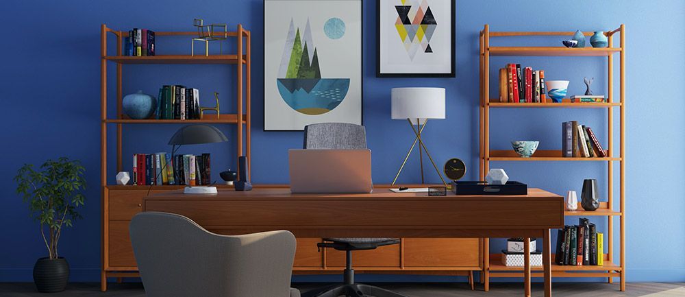 Un bureau à domicile avec un mur bleu, un bureau, des étagères, des œuvres d'art, un ordinateur portable et une chaise.