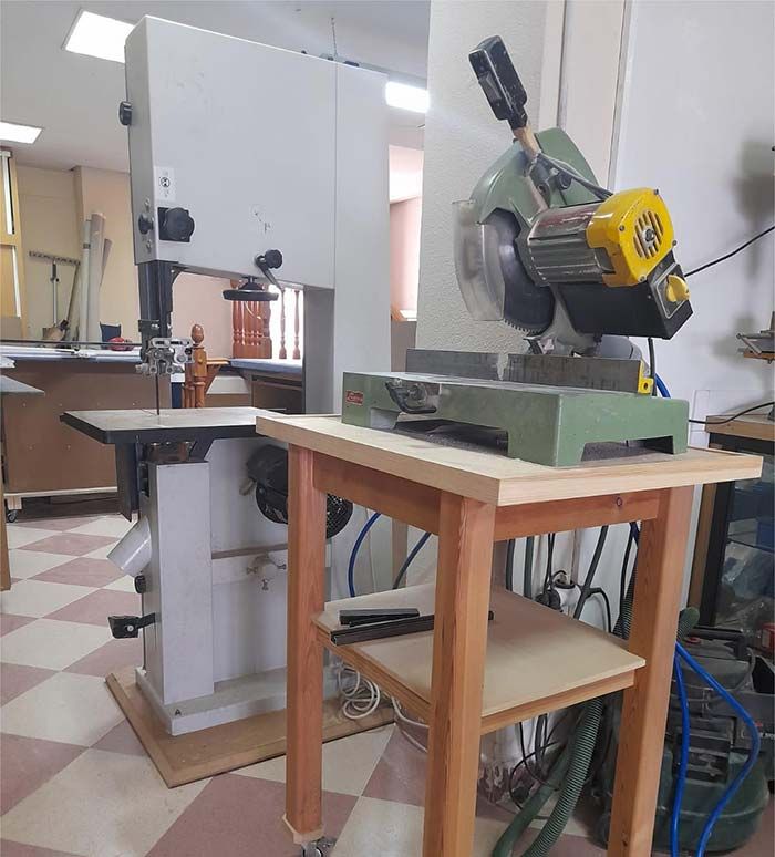 Una sierra de cinta se encuentra sobre una mesa de madera en un taller.