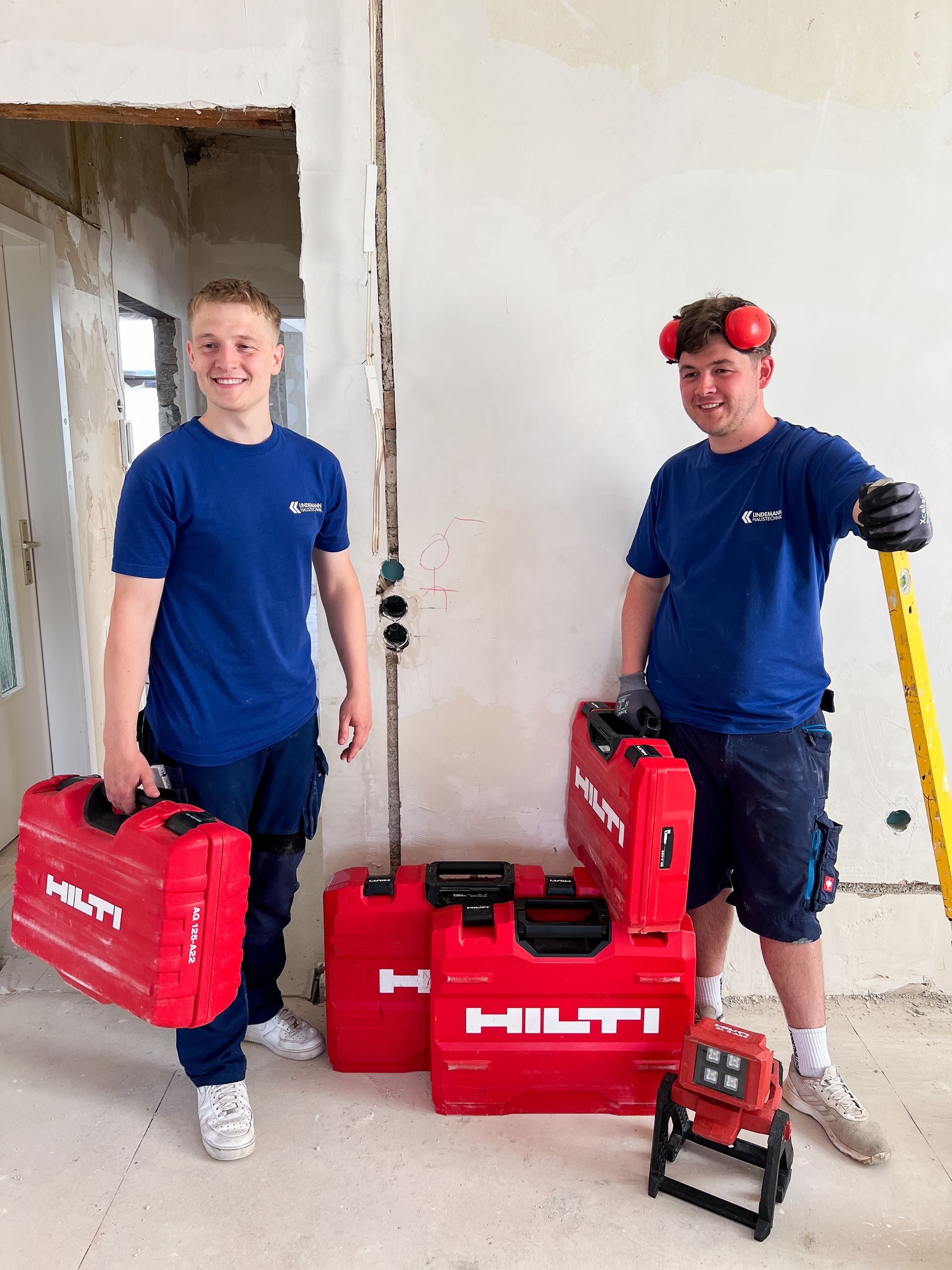 Zwei Männer stehen nebeneinander in einem Raum und halten Werkzeuge in den Händen.
