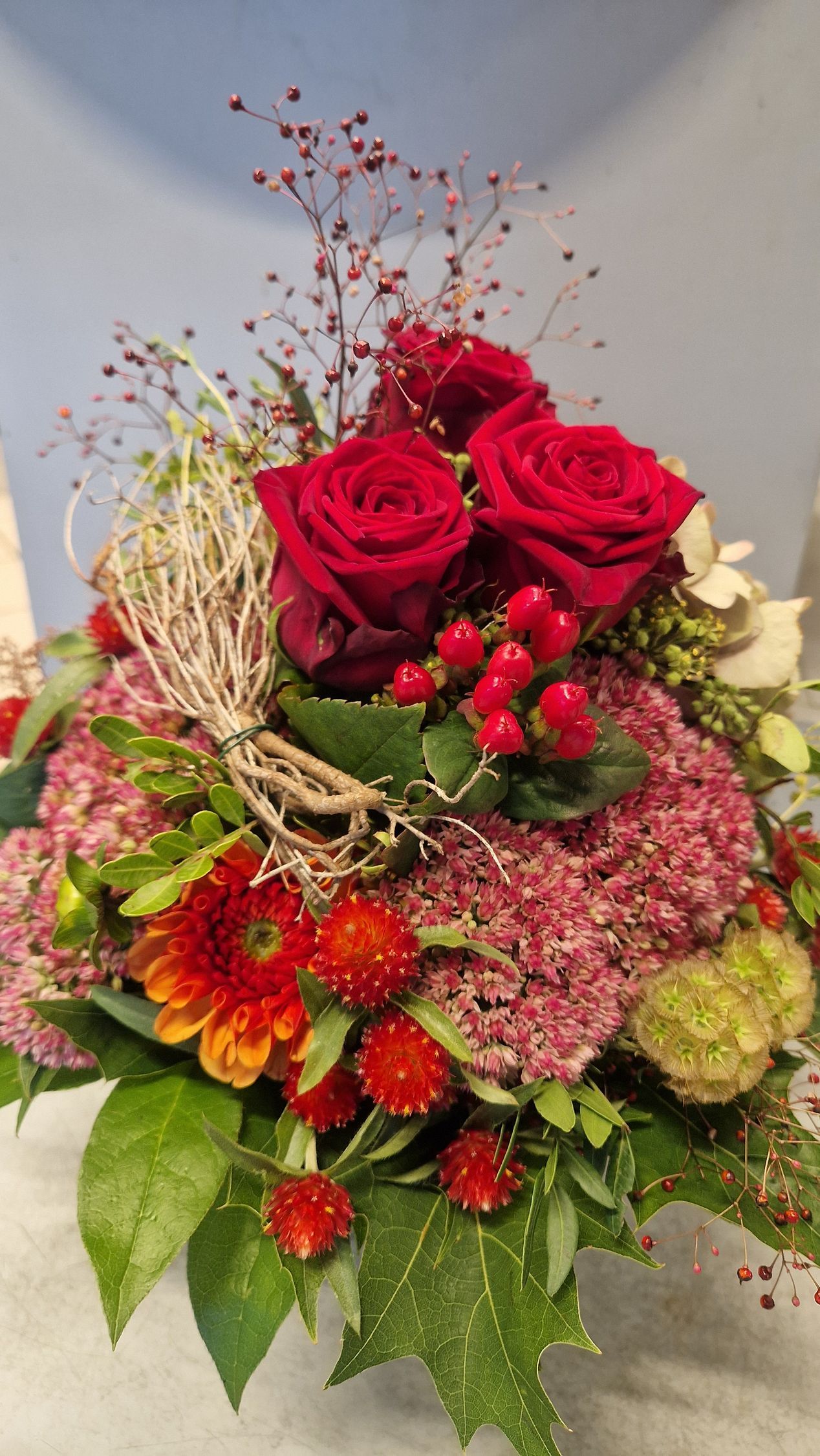 Rote Rosen und andere Herbstblumen in einem dekorativen Arrangement.