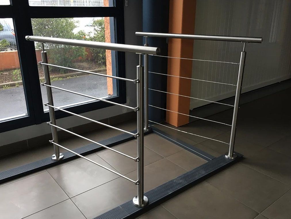 Rambarde en acier inoxydable avec câbles horizontaux devant une fenêtre, à l'intérieur.