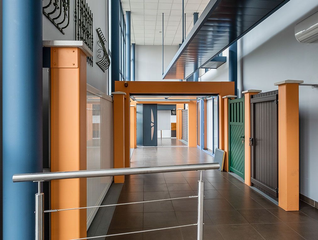 Couloir intérieur avec portes et piliers dans les tons orange, vert et marron.