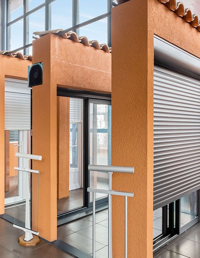 Des murs orange laissent apparaître des volets roulants blancs et gris.