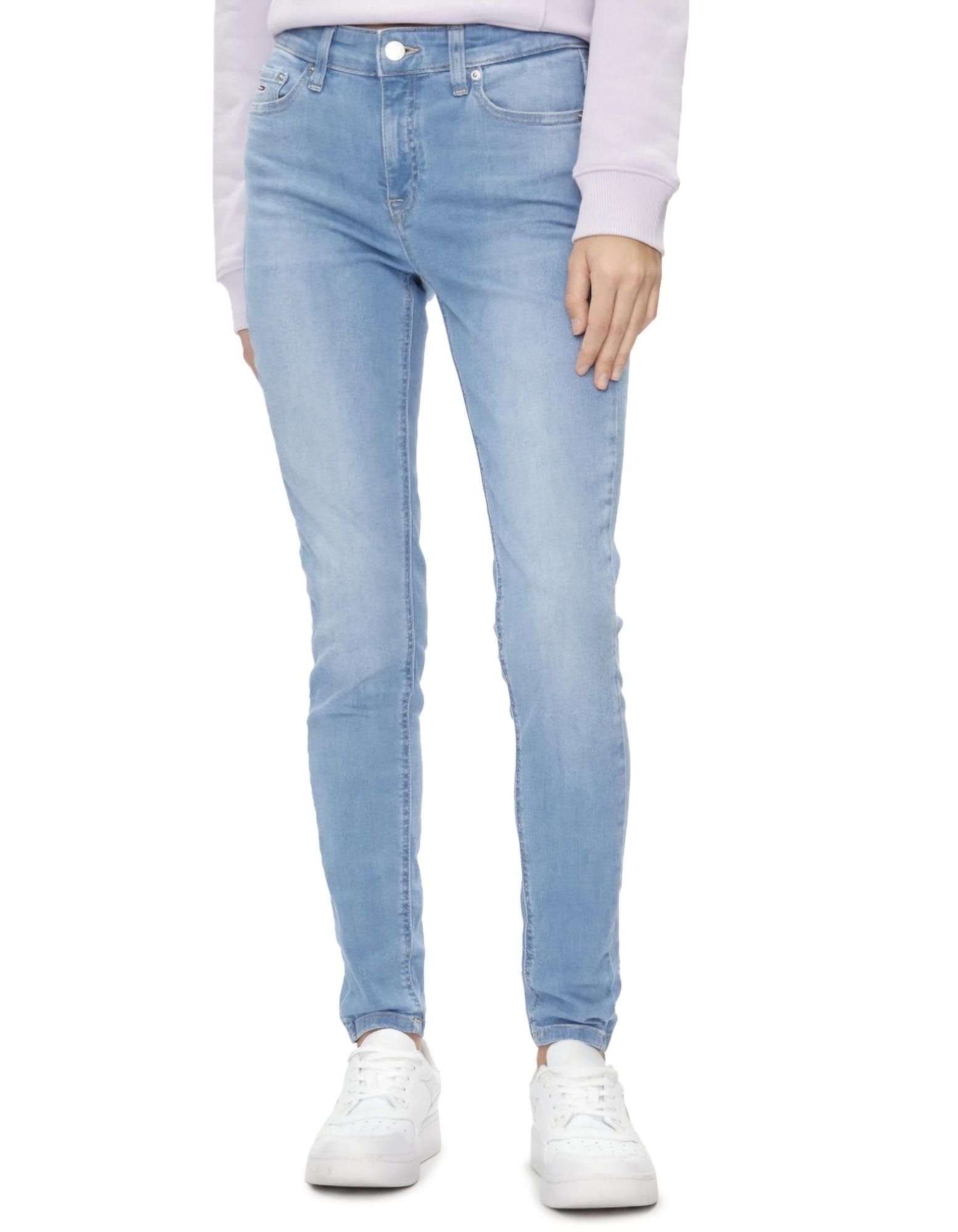 Una mujer lleva jeans azul claro y zapatillas blancas.