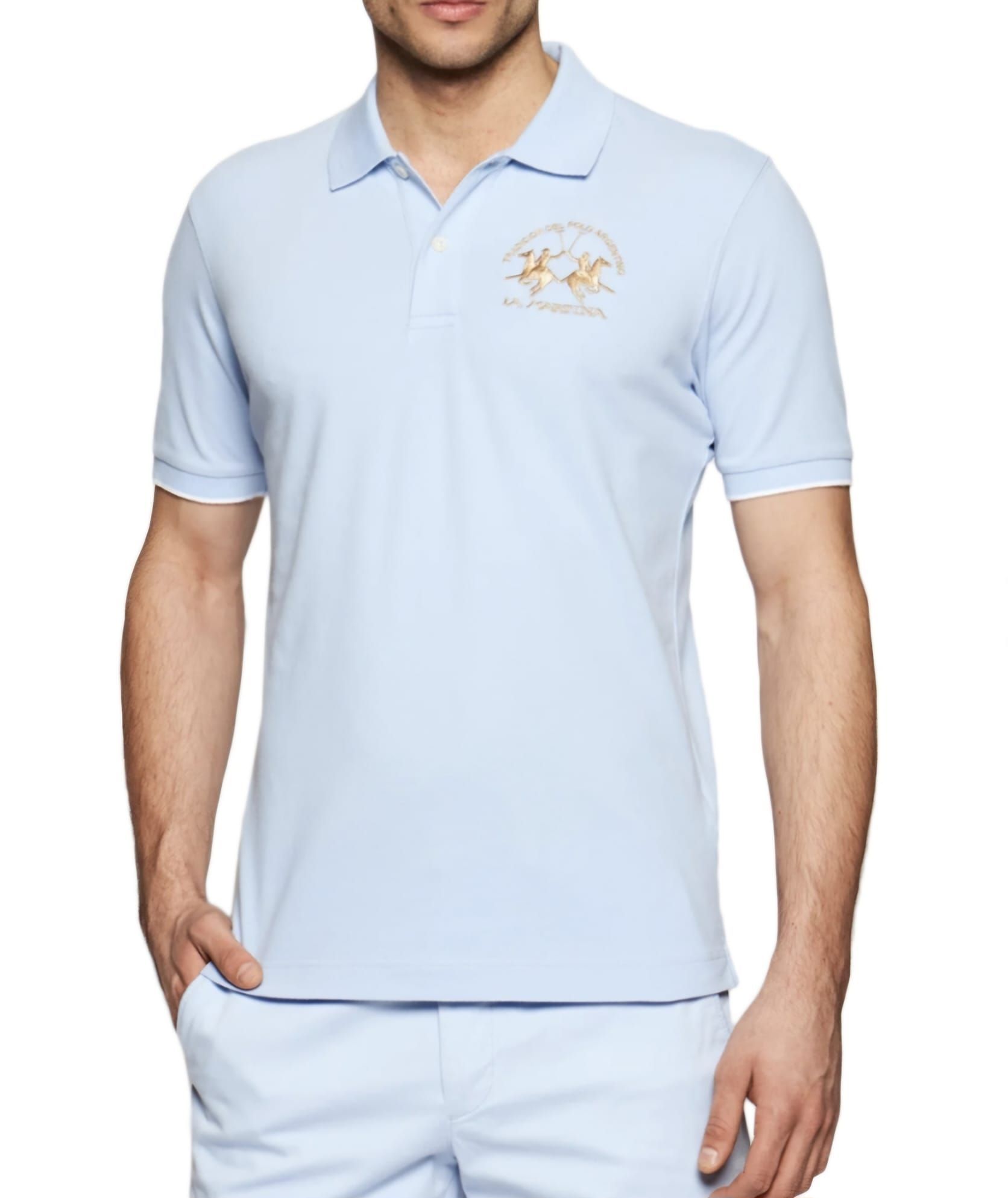 Un hombre lleva un polo azul claro y pantalones cortos.