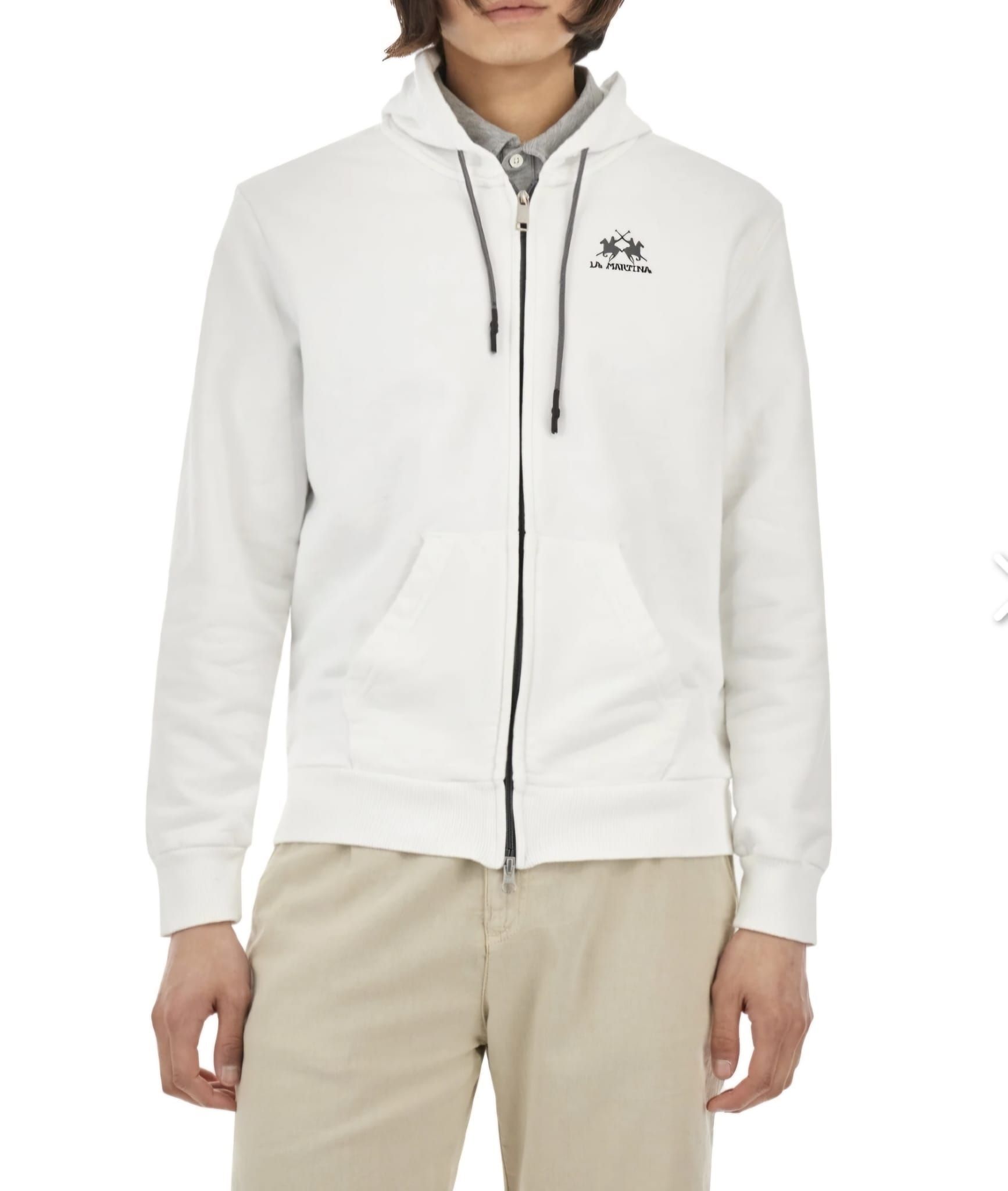 Un hombre lleva una sudadera blanca con cremallera.