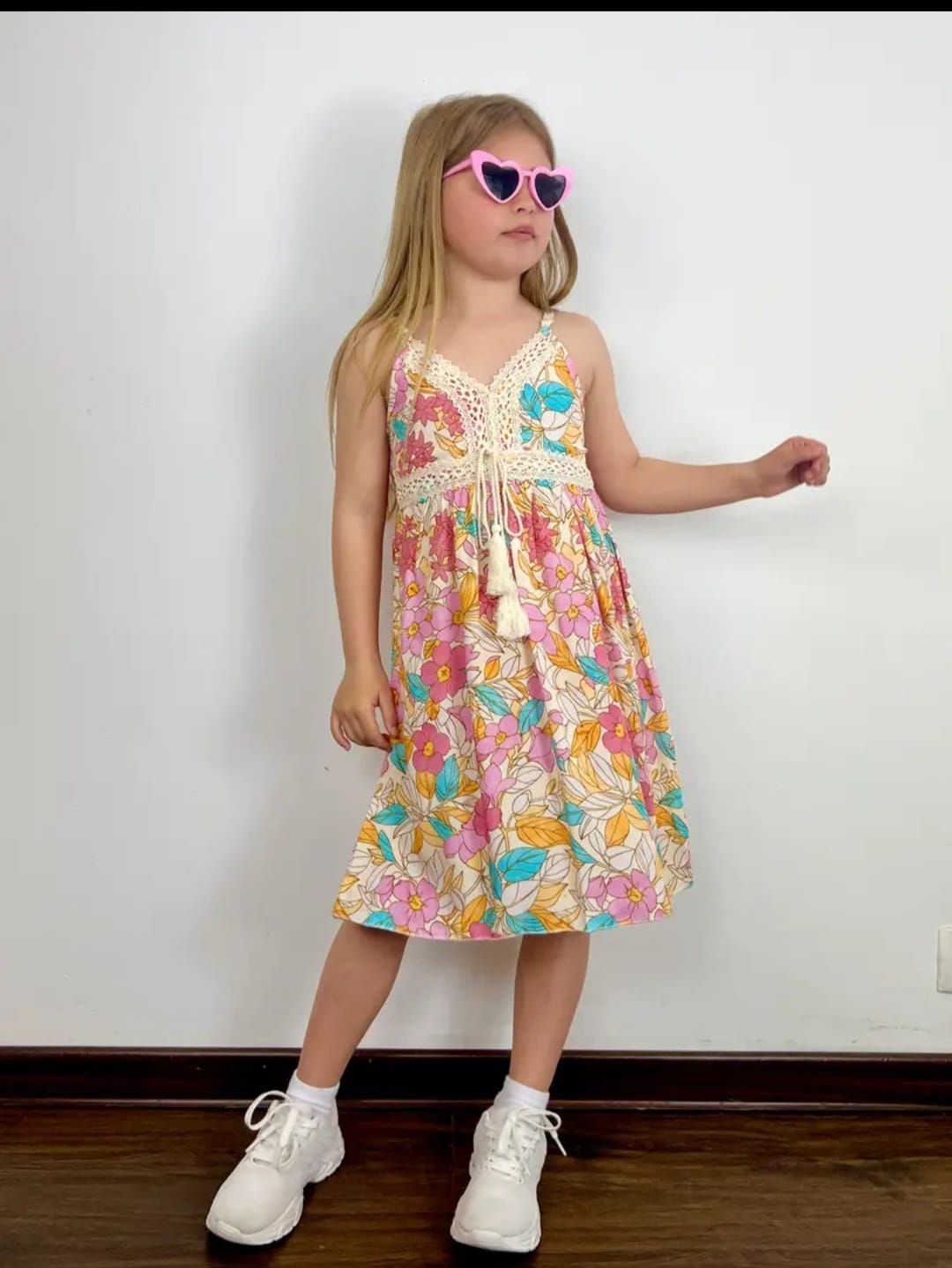 Una niña lleva un vestido floral y gafas de sol.