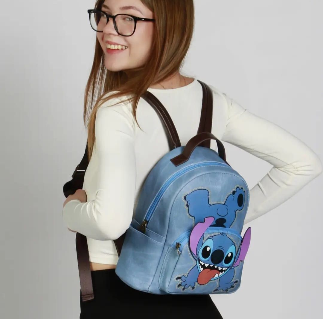 Una mujer con gafas y una mochila azul con una puntada.