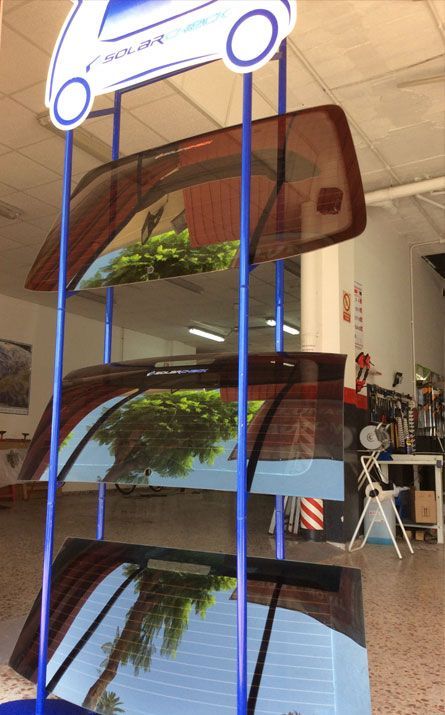 Una exhibición de un automóvil con el reflejo de un árbol en el parabrisas.