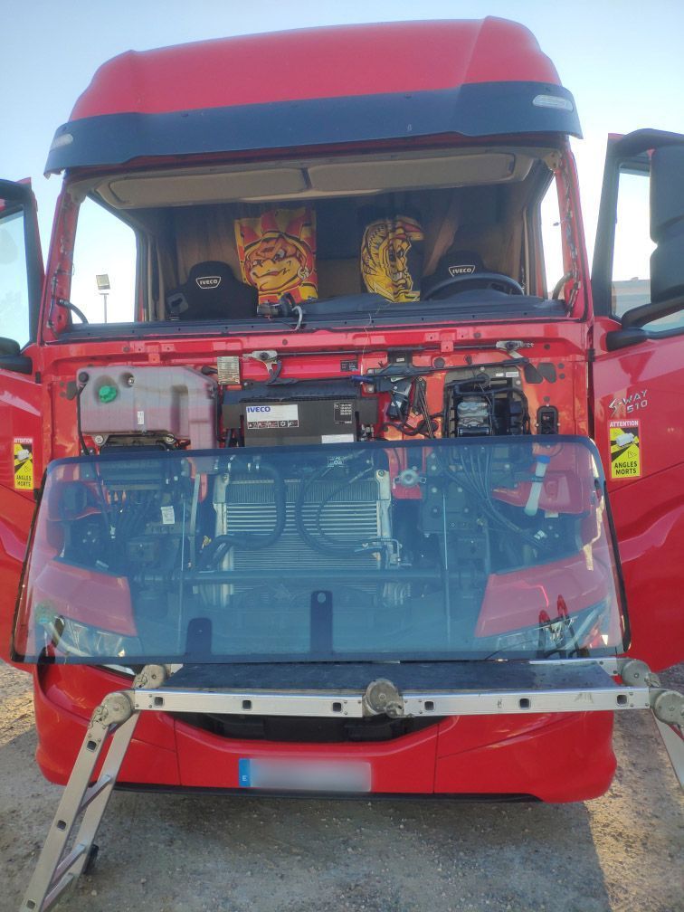 El frente de un camión rojo sin el parabrisas.