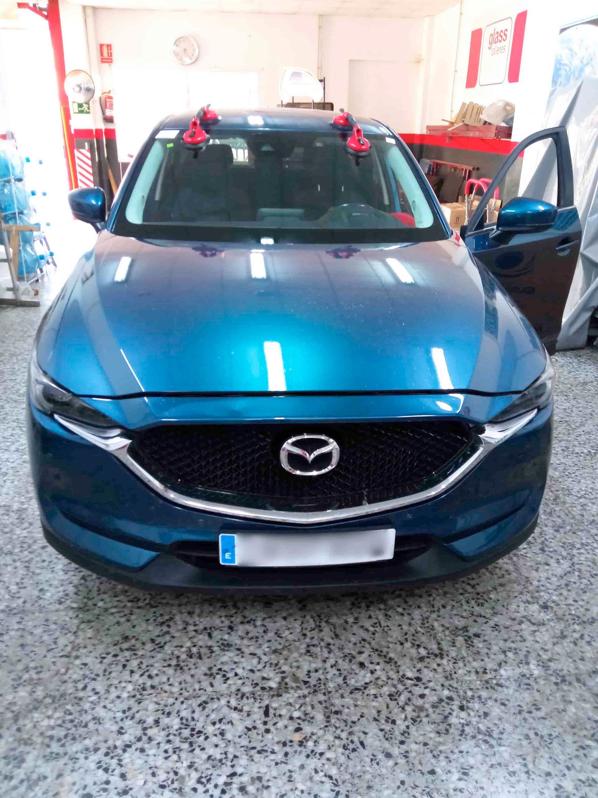 Un coche Mazda azul está aparcado en un garaje.
