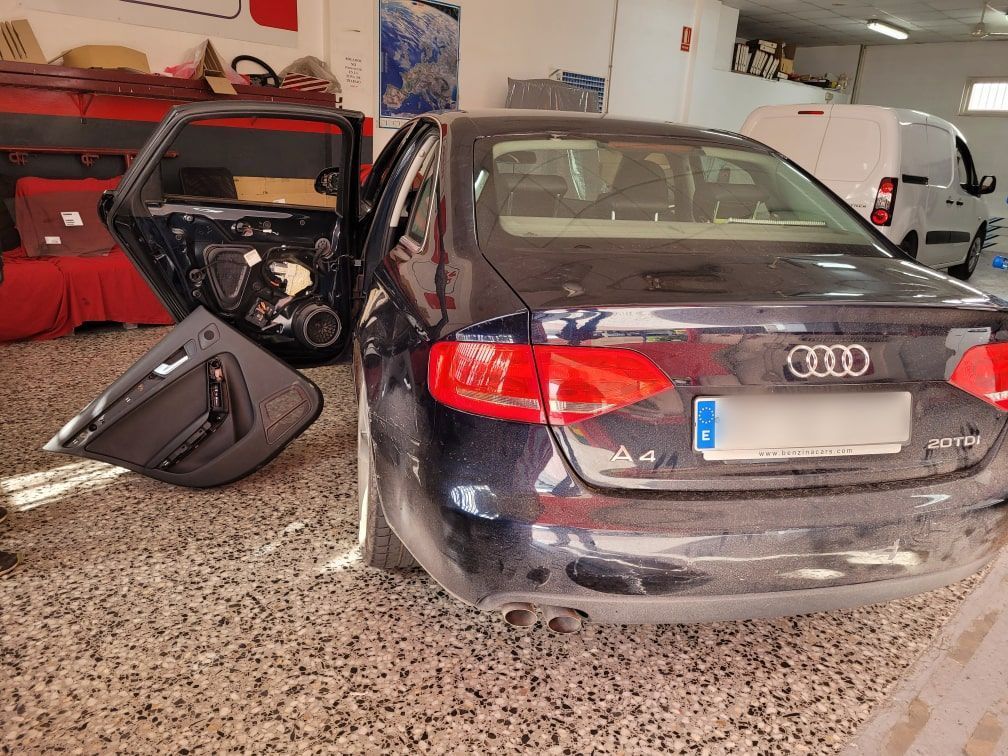 Un coche Audi negro está aparcado en un garaje con las puertas abiertas.