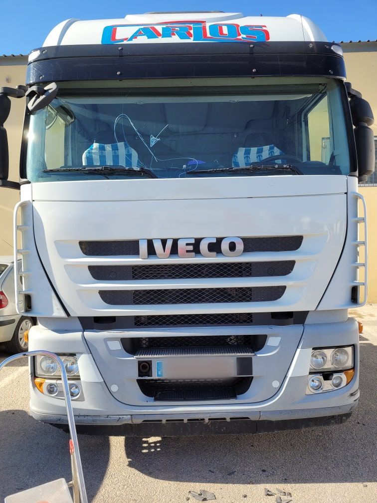 Un camión Iveco blanco está estacionado frente a un edificio.