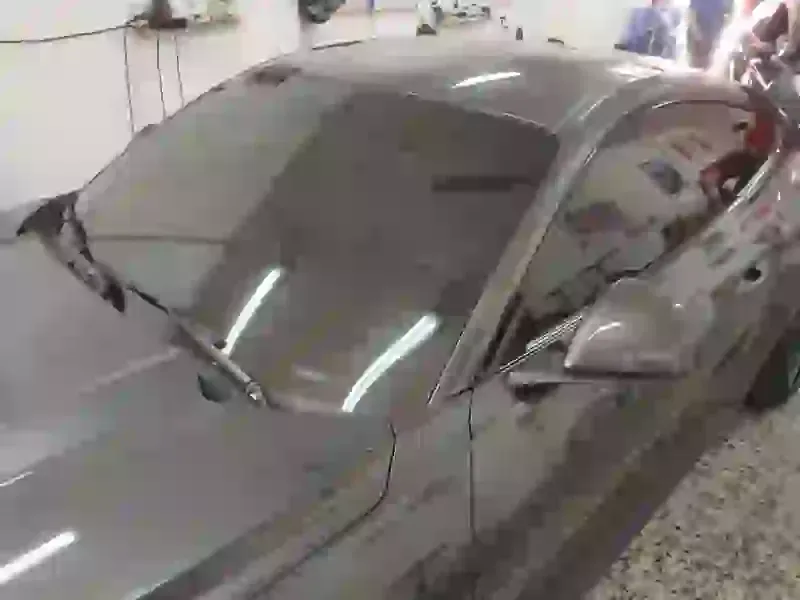 Un coche deportivo gris está aparcado en un garaje.