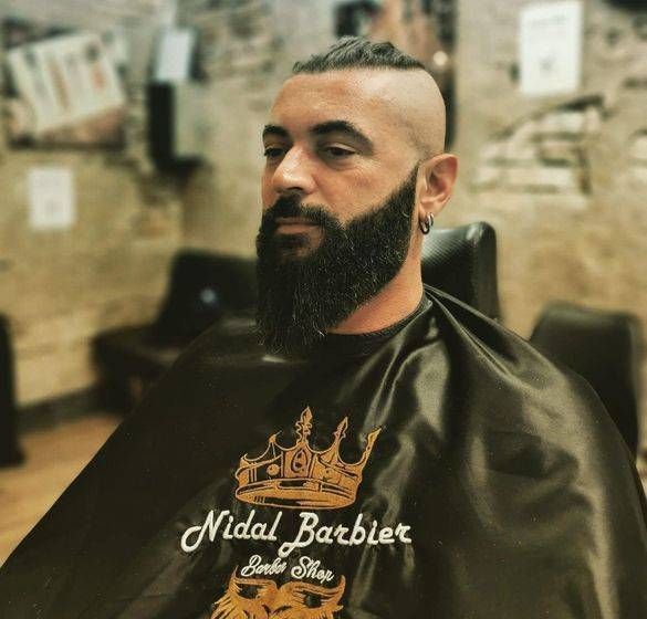 Un homme avec une barbe se fait couper les cheveux par nidal barbier