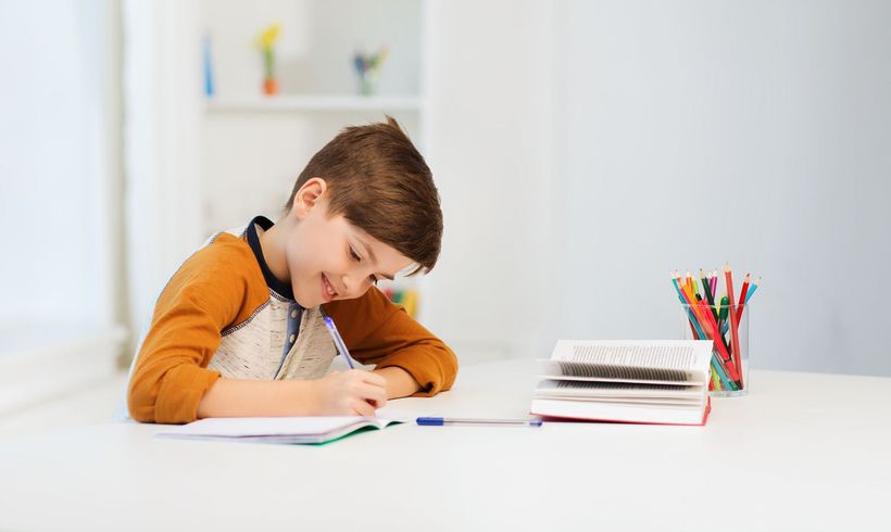 Jeune garçon souriant qui écrit