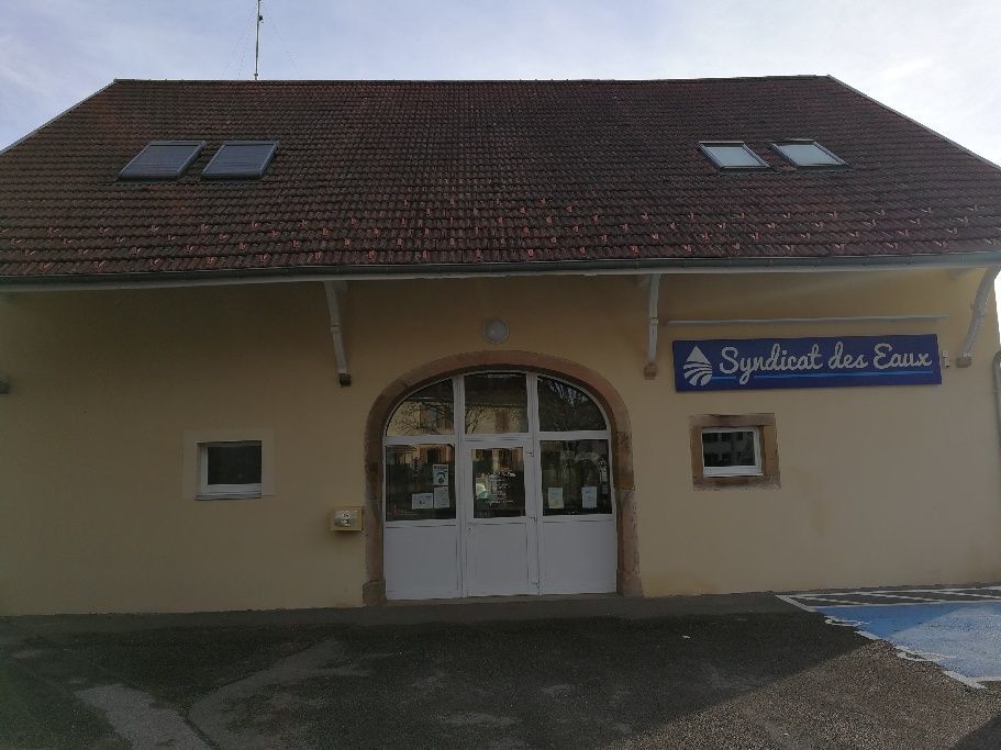 Un bâtiment avec une enseigne et une camionnette blanche garée devant, sous un ciel sombre.