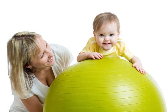 Frau schaut Baby auf einem Gymnastikball an