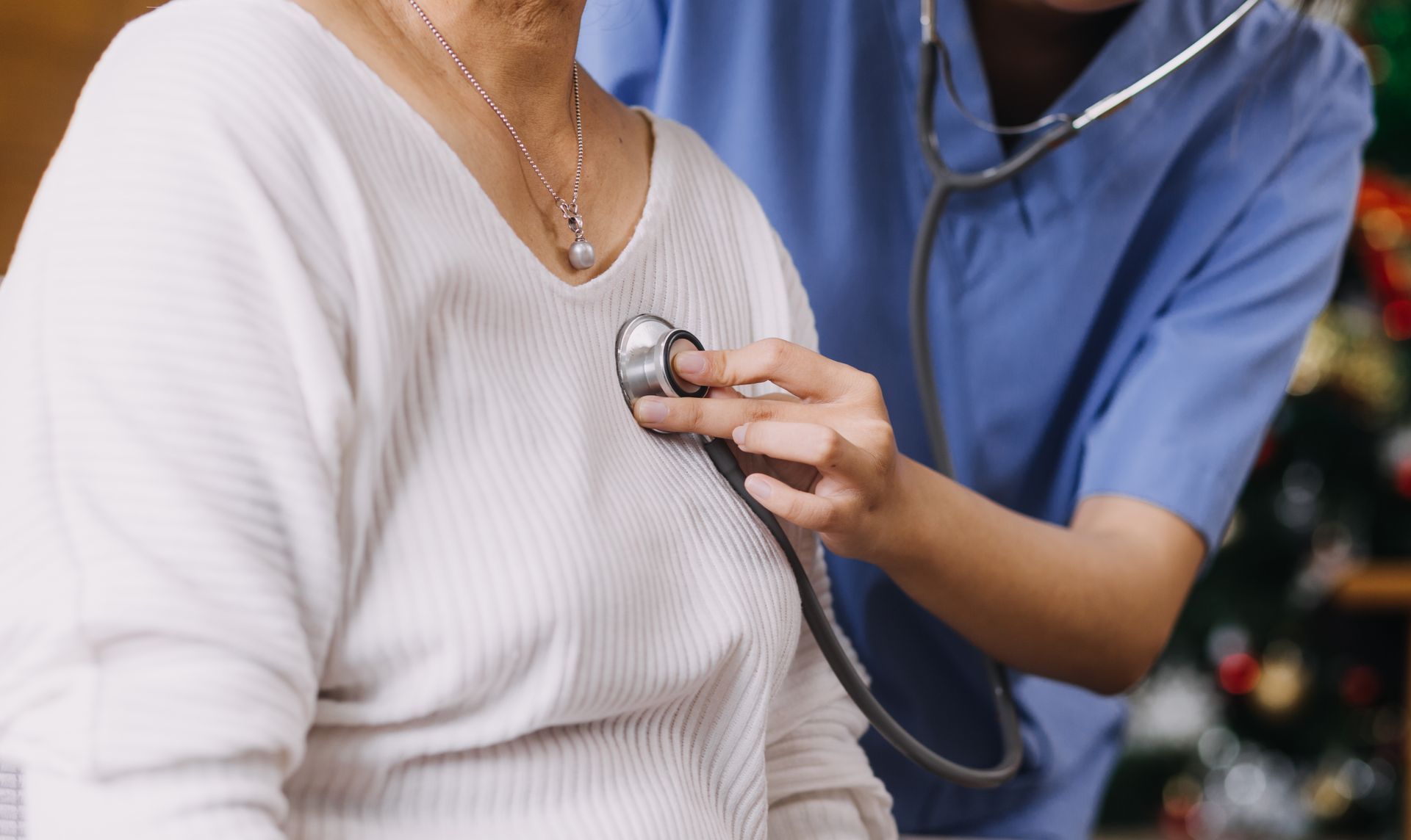 Une personne vêtue d'une blouse bleue utilise un stéthoscope pour écouter la poitrine d'une autre personne.