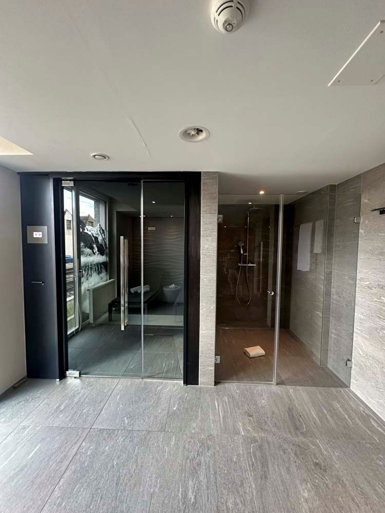 Ein großer leerer Raum mit einer Glastür und einem Rauchmelder an der Decke.