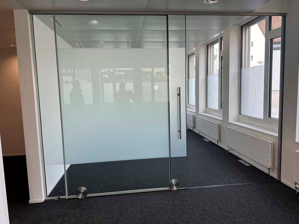 Ein Raum mit einer Glastür und vielen Fenstern.