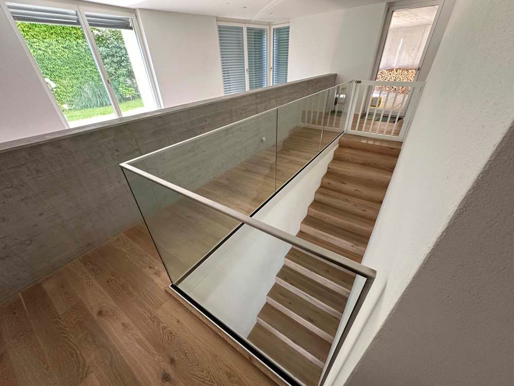 Eine Treppe mit Glasgeländer und Holzstufen