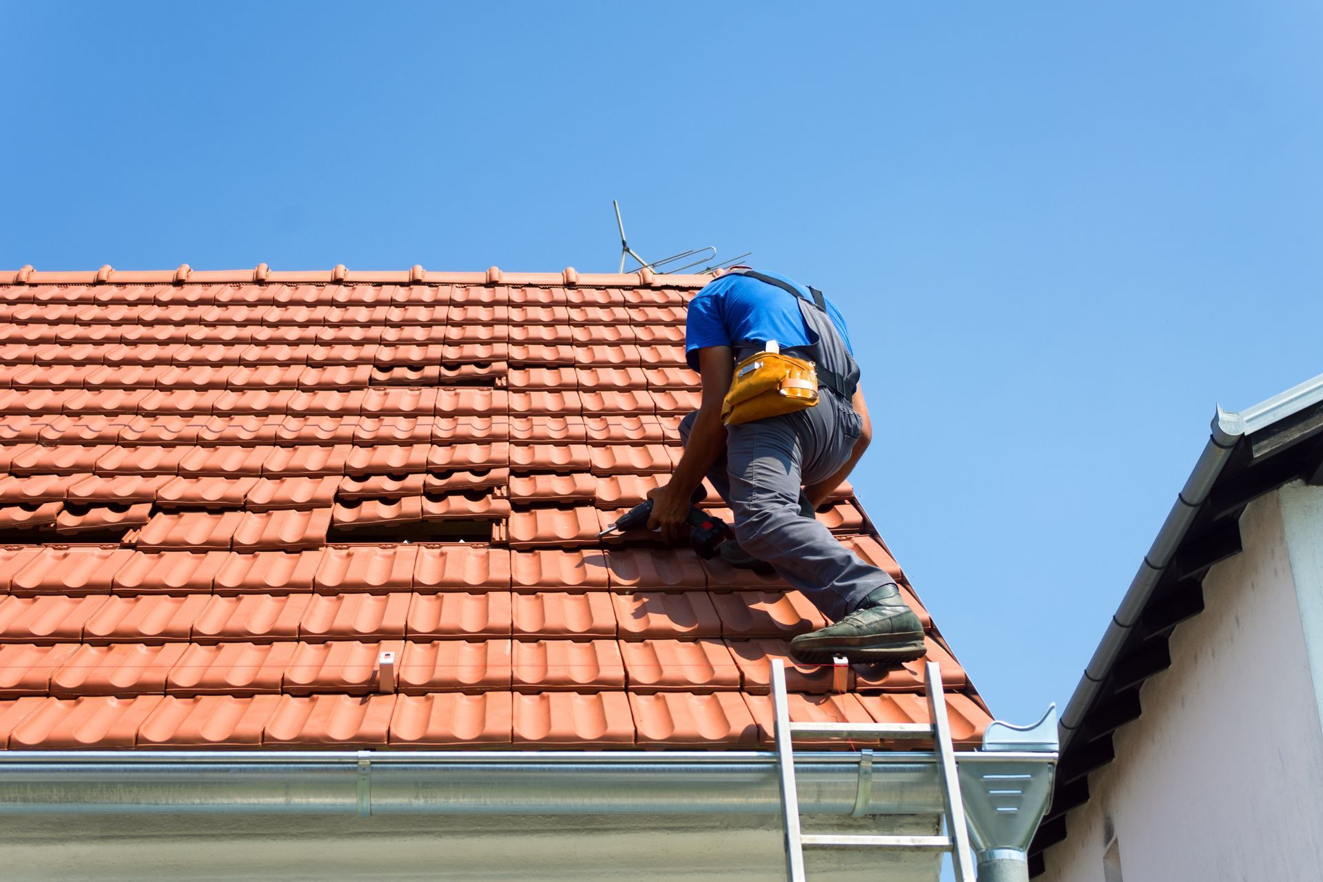 Un couvreur sur un toit posant des tuiles